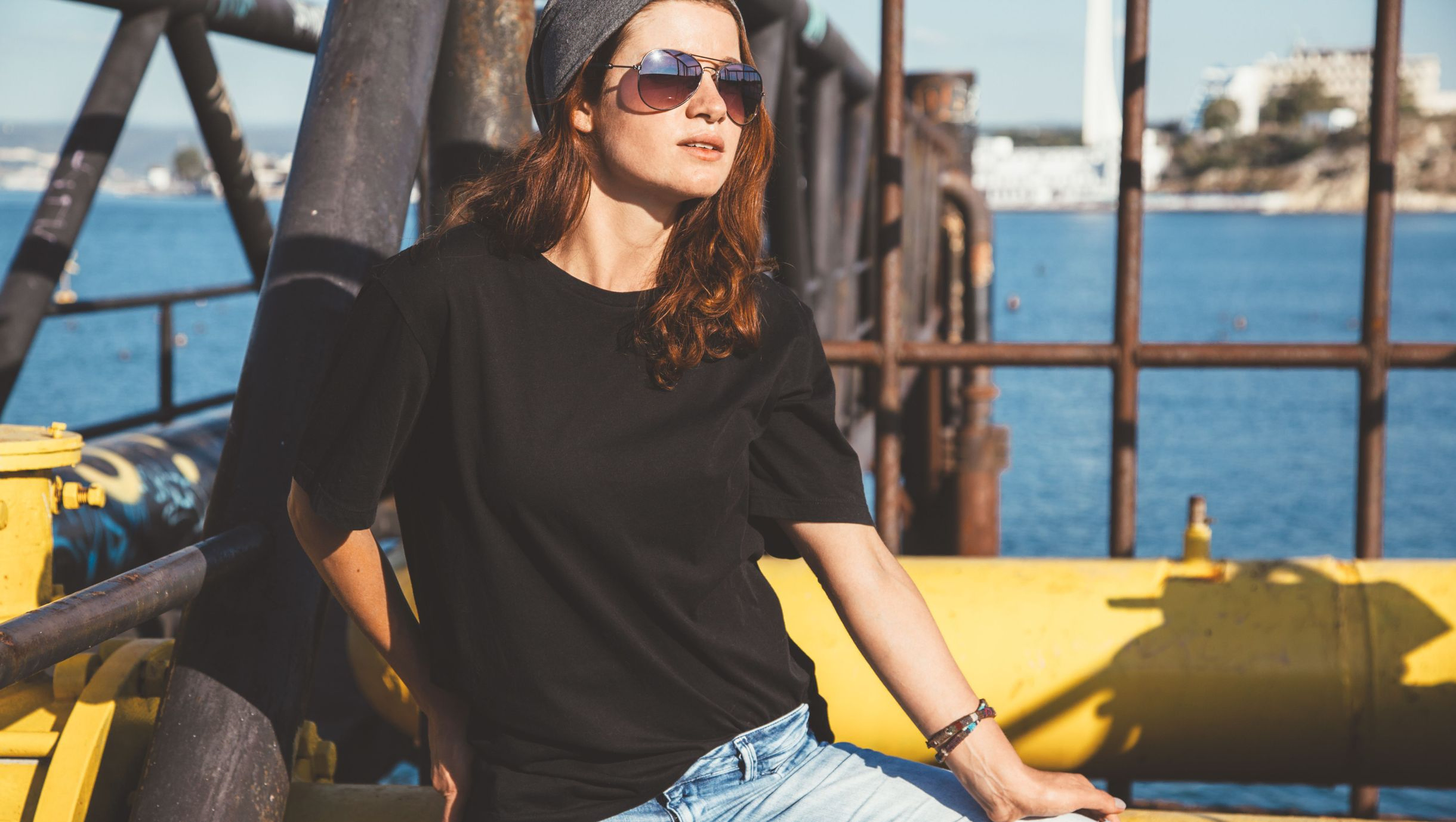 chica con gafas de sol posando cerca del mar